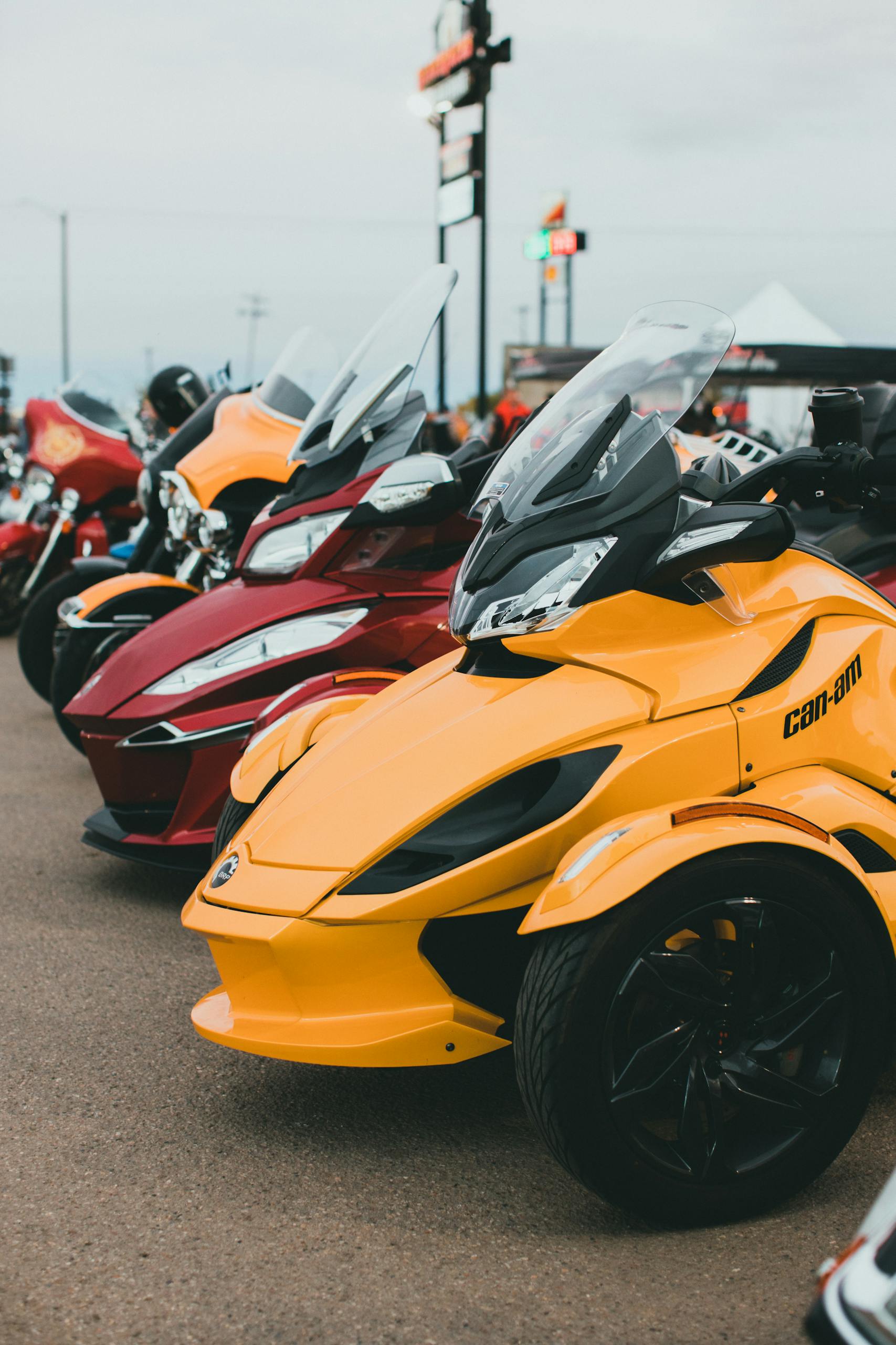 A vibrant display of Can-Am Spyder motorcycles parked on a concrete pavement outdoors.